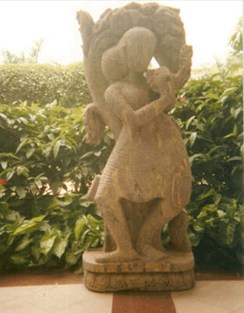 Dynamic pink marble Hanuman sculpture in devotional pose with detailed muscular definition and traditional iconography